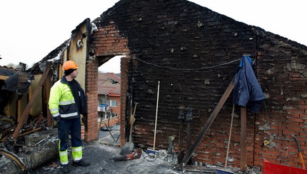 Brandman tittar på utbränt hus