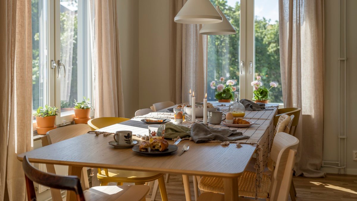 Ett matbord med fönster vid både kortsidan och långsidan. På bordet är det uppdukat med frukost.