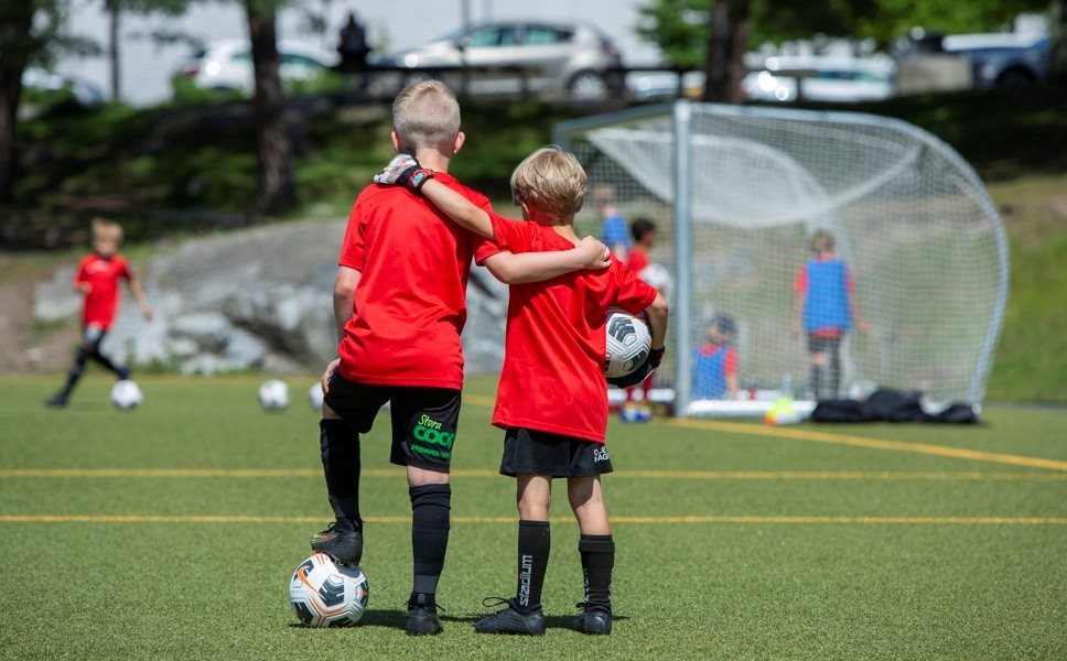 Två killar med fotbollar och armarna om varandras axlar