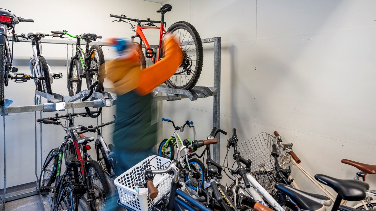 Man lyfter ner cykel från hylla i cykelrum